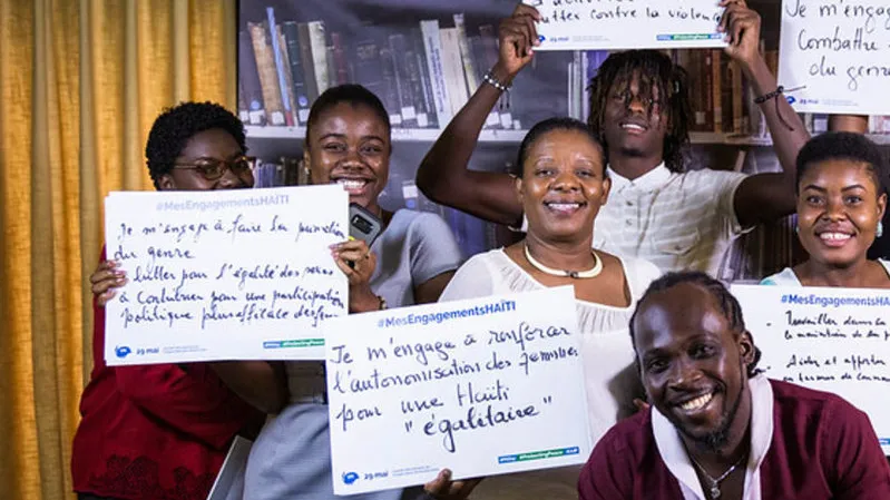 A group of people holding pieces of paper with wording on it smiling