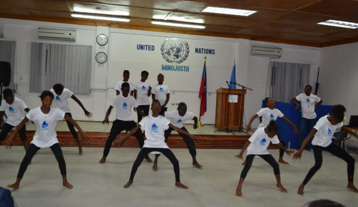 Pour la Journée des Casques bleus, les policiers internationaux de la MINUJUSTH ont célébré la richesse et la diversité des cultures traditionnelles avec de jeunes danseurs haïtiens en partageant des danses haïtiennes, indiennes et népalaises.‬ © UNPOL Comlan Flavien Dovonou / UN / MINUJUSTH, 2018