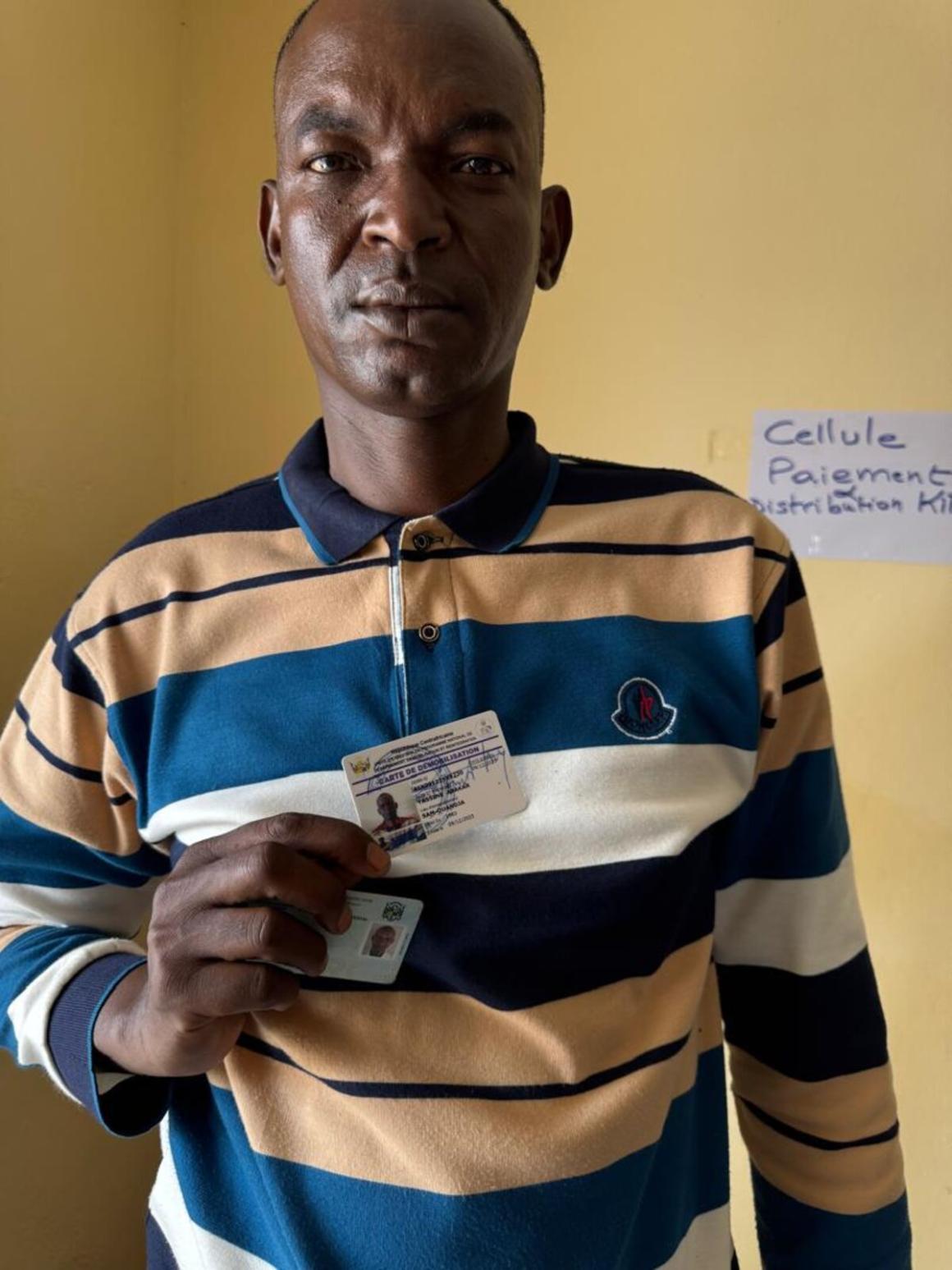 A man holds up an ID card